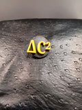 Black round Delta C squared badge with raised gold lettering