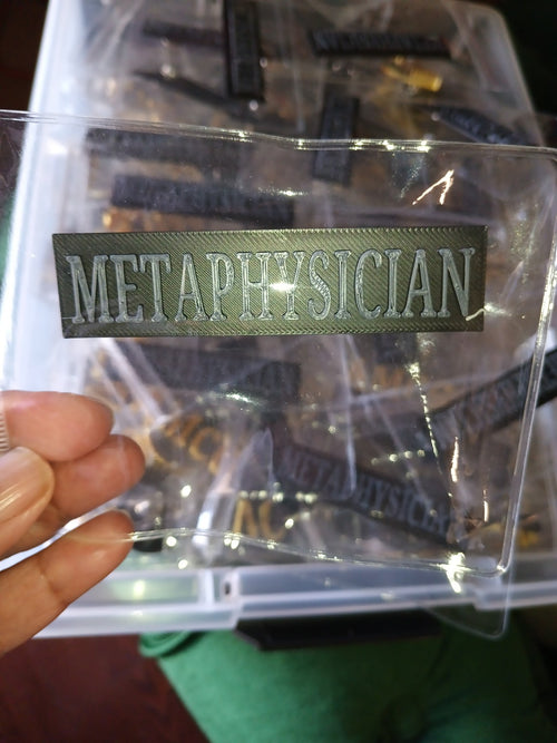 Black and gray Metaphysician 3D-printed badge