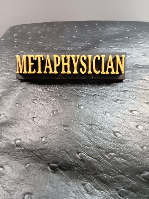 Black Metaphysician lapel pin with hand-finished gold lettering
